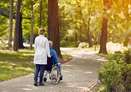 Nurse pushing elderly man in wheelchair home health care Gracia Hospice